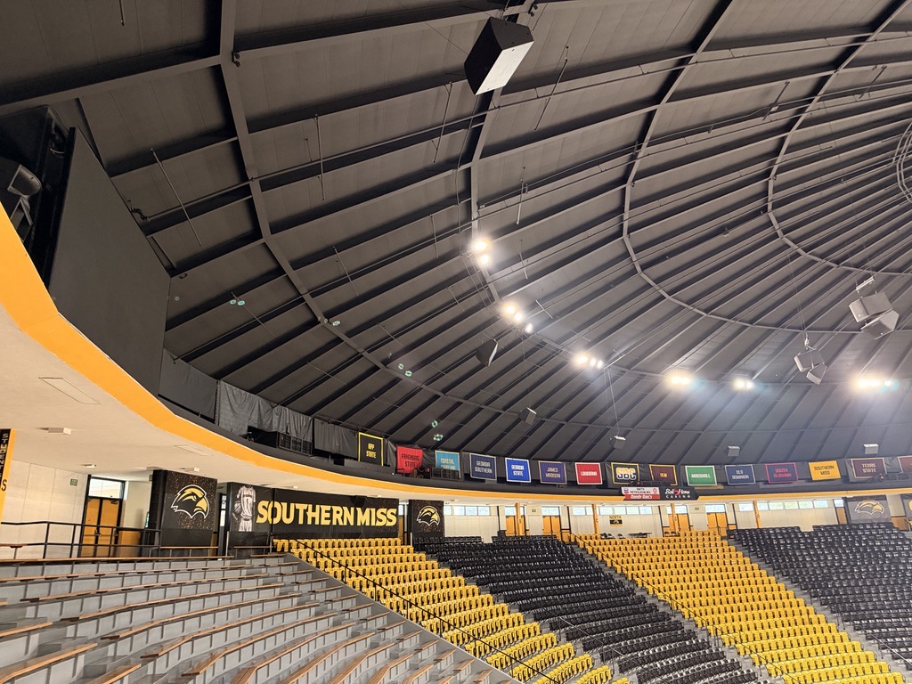 Inside Reed Green Coliseum, looking up at the coated roof deck and structural steel over the arena seating