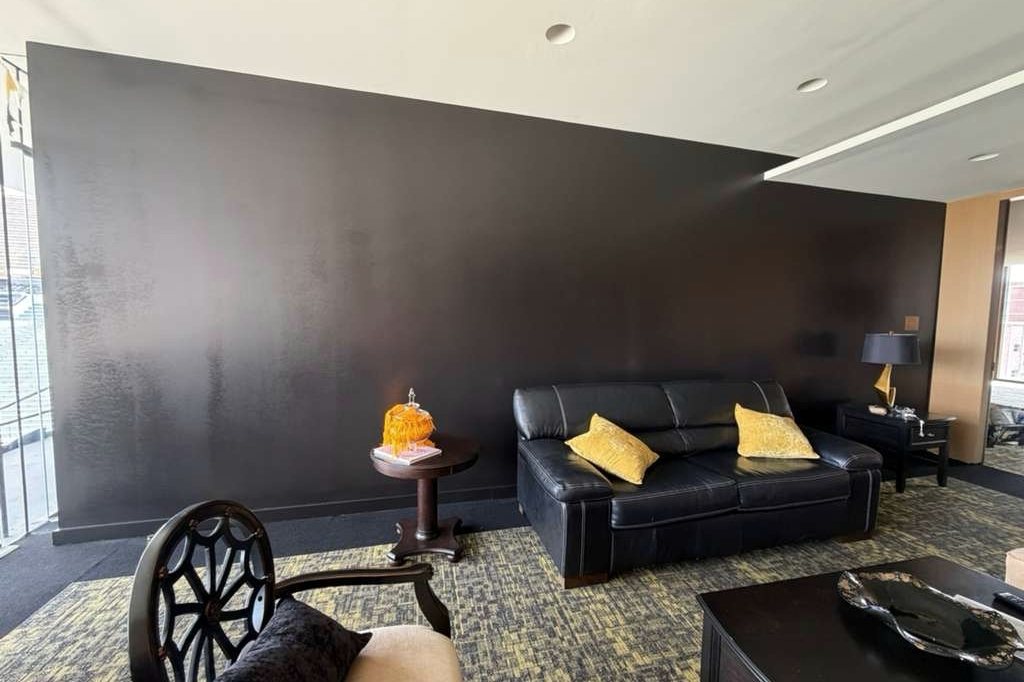 Stadium suite lounge with a dark painted feature wall and leather sofa