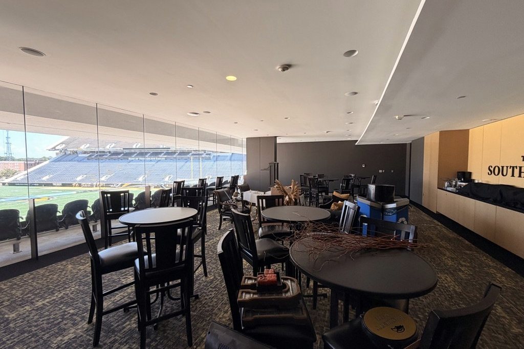 Suite interior with high-top seating and a glass wall over the football field