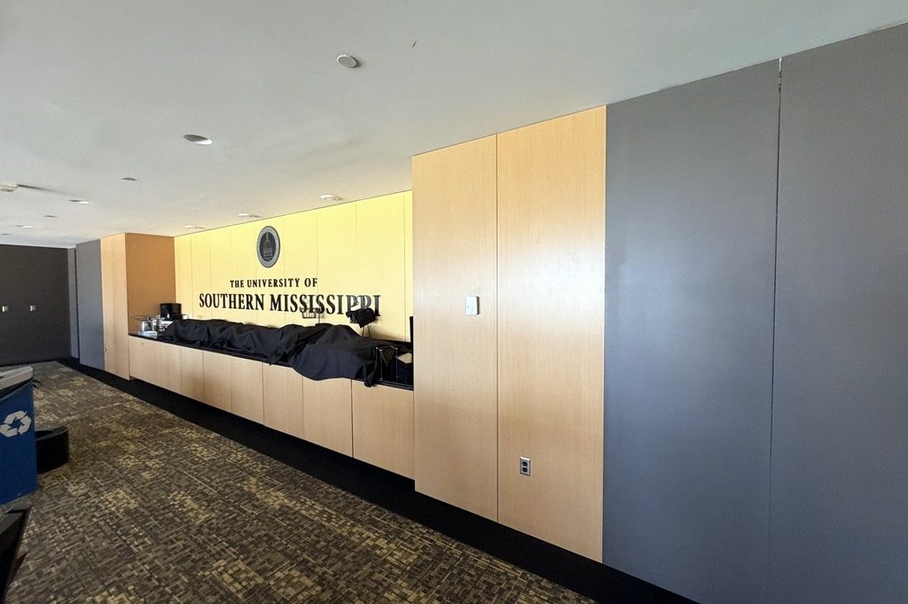 Suite bar wall with University of Southern Mississippi lettering, wood cabinetry, and grey painted panels
